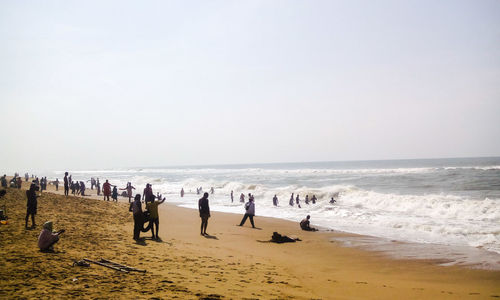 People on beach against clear sky