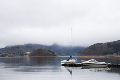 Sailboats moored in lake against sky