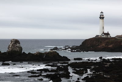 Lighthouse by sea against sky