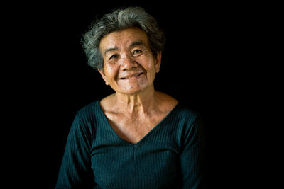 Portrait of smiling woman against black background