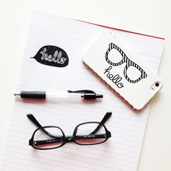 Hello text printed mobile phone on notepad with eyeglasses and pen