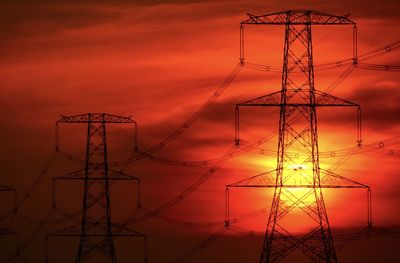 Low angle view of silhouette electricity pylon against sky during sunset