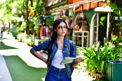 Young woman holding map while standing outdoors