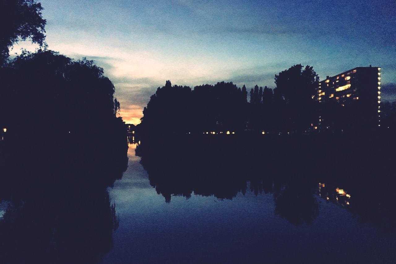 illuminated, reflection, architecture, building exterior, tree, built structure, sky, water, night, dusk, silhouette, waterfront, river, lake, outdoors, city, cloud - sky, no people, religion, travel destinations