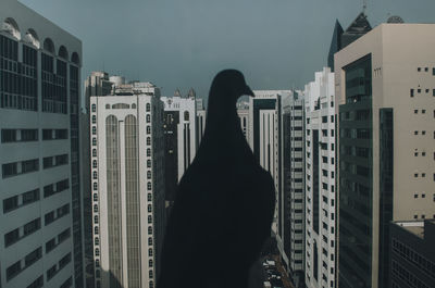 Rear view of man standing by buildings against sky