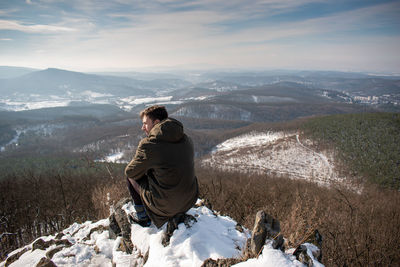 Woman looking at mountains against sky during winter