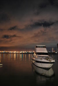 Boats in sea against cloudy sky at sunset