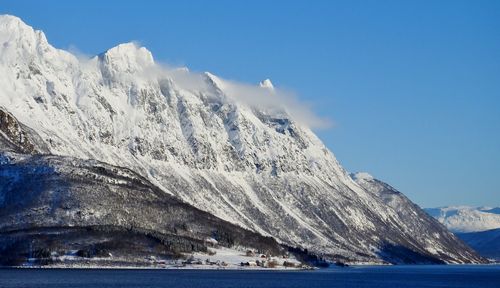 Scenic view of snow covered mountain by sea against sky