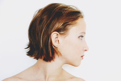 Close-up of beautiful young woman with short haircut in profile against white background