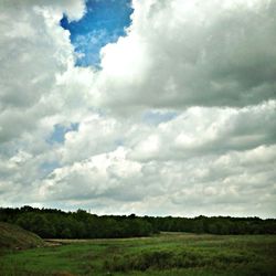 Scenic view of grassy field against cloudy sky