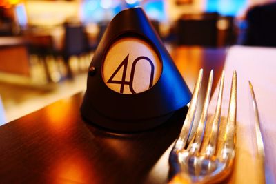 Close-up of number tag and forks on illuminated table
