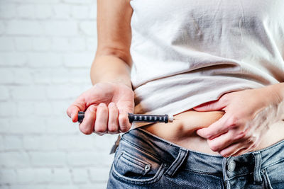 A woman injects insulin with insulin injection device into the subcutaneous tissue of abdomen