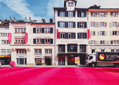 Buildings by street against sky in city