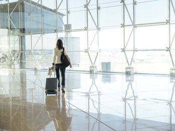 Woman walking with suitcase at the departure hall of the airport.