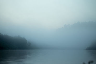 Scenic view of lake against sky during foggy weather