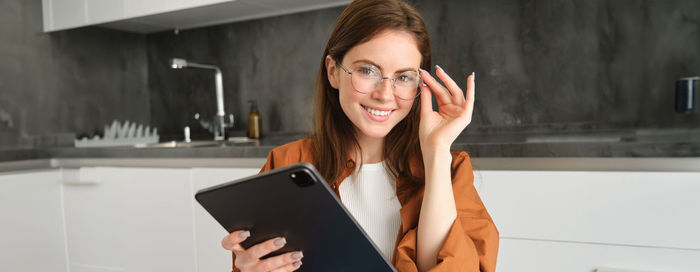 Young woman using mobile phone while standing in office