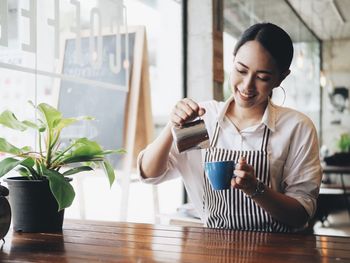 Young woman holding drink in cafe