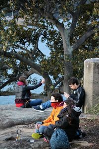 Rear view of woman sitting on tree