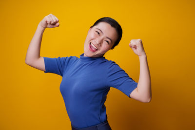 Portrait of smiling man standing against yellow background