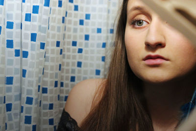 Close-up of young woman against curtain