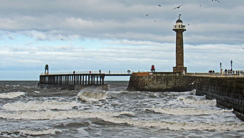 Lighthouse by sea against sky