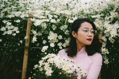 Close-up of young woman wearing eyeglasses with flowers