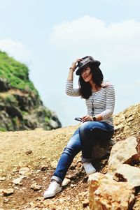 Portrait of a smiling young woman sitting on rock