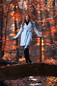 Portrait of woman standing in forest during autumn