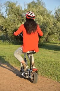 Rear view of woman riding bicycle on footpath