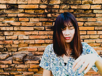 Beautiful young woman against brick wall