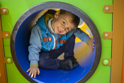 Portrait of boy smiling while sitting in play equipment