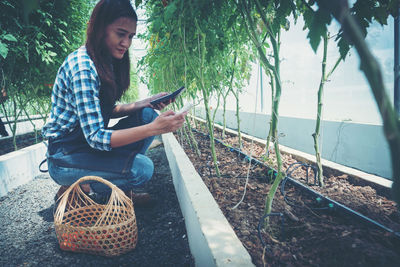 Side view of young woman sitting on plant