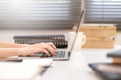 Midsection of person using laptop on table