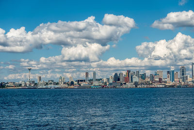 City at waterfront against cloudy sky