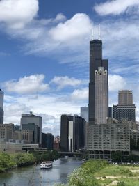 River by modern buildings against sky in city