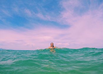 Young woman swimming in infinity pool against sky