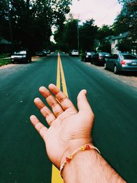 Cropped image of hand with street in background