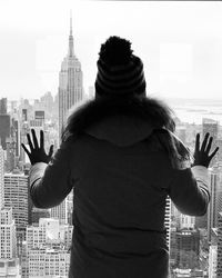 Rear view of woman standing against buildings in city