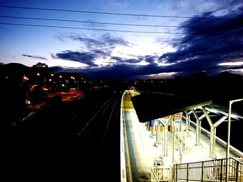 Illuminated railroad tracks against sky at night