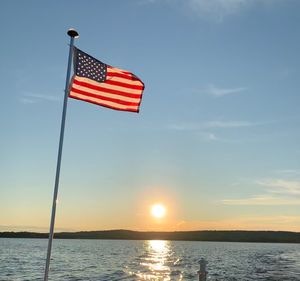 Red flag on pole against sky during sunset