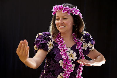 Close-up of woman wearing flowers while dancing against wall