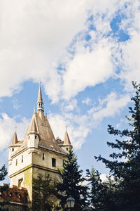 Low angle view of trees and building against sky