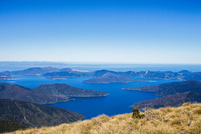 Scenic view of lake and mountains against clear blue sky