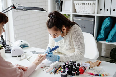 Young woman wearing glove and mask working at salon