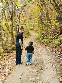 Rear view of friends walking in forest during autumn