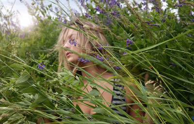 Close-up of young woman with flowers in grass