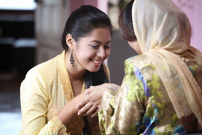 Close-up of mother and daughter holding hands at home