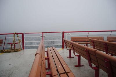 Empty benches in ferry against clear sky