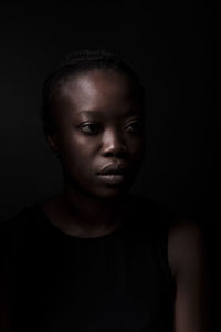 Close-up portrait of young woman against black background