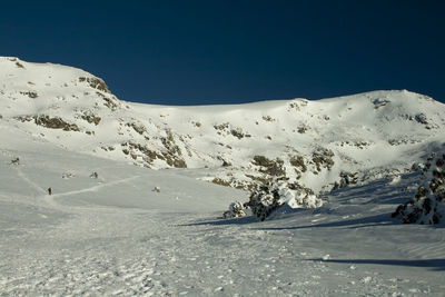 Scenic view of snowcapped mountains against clear blue sky